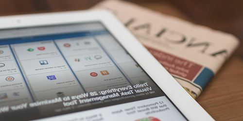 white tablet computer on top of newspaper
